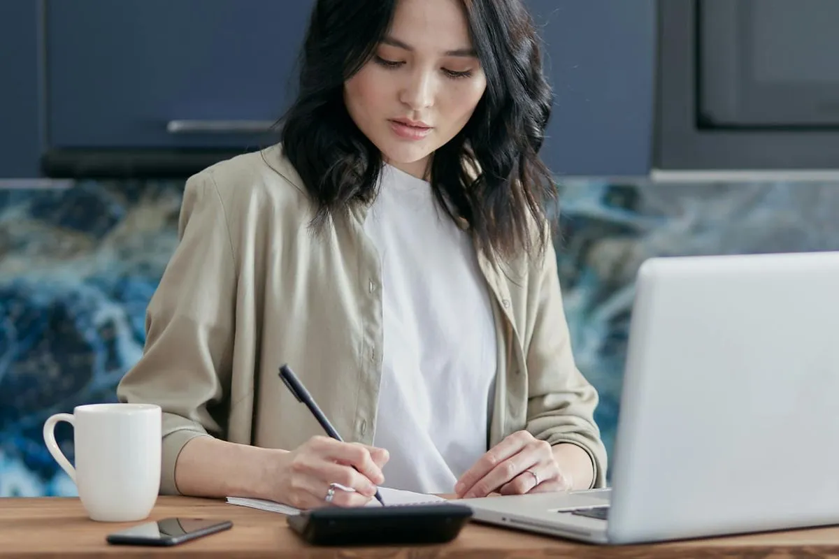 Woman writing list debt on notebook