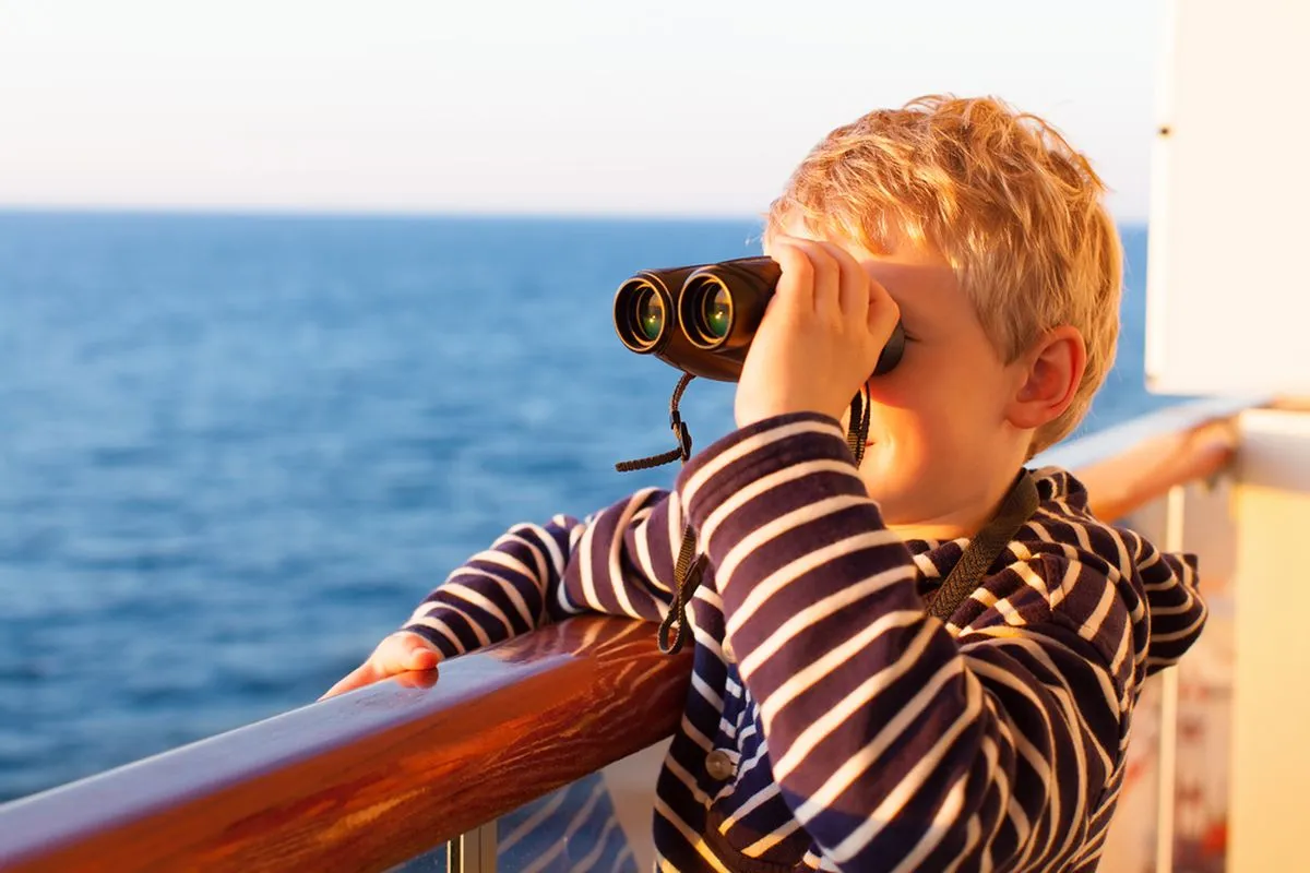 child looking out to sea using binoculars
