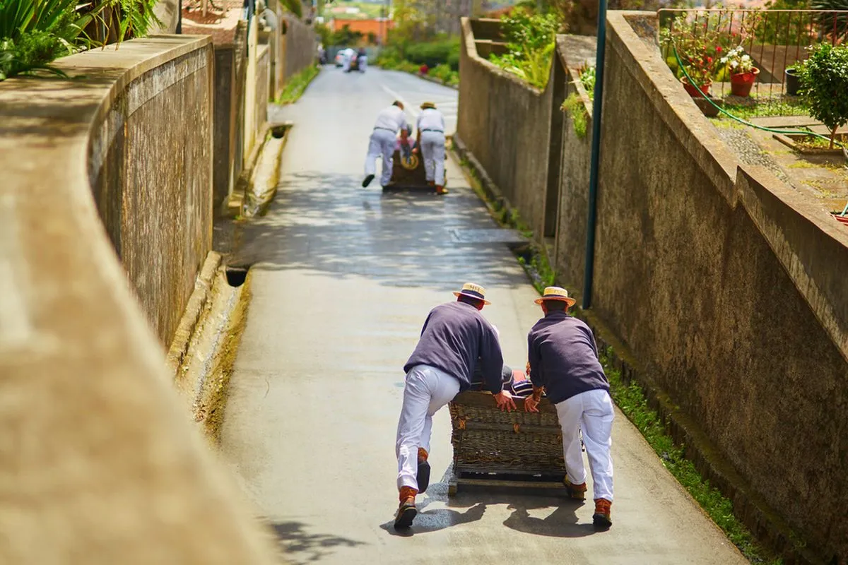 Two people pushing a toboggan down the hill in Funchal