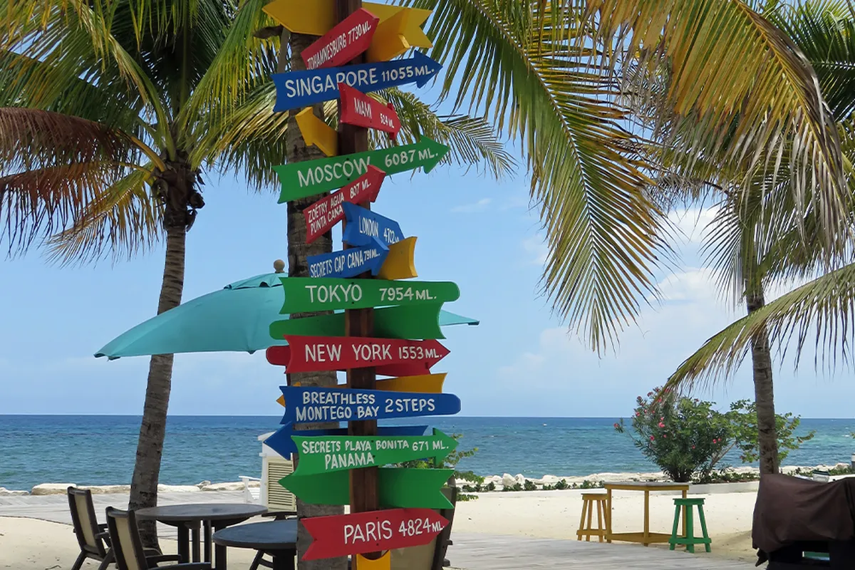 Colorful signpost on a beach with distances to various cities in Montego Bay, Jamaica