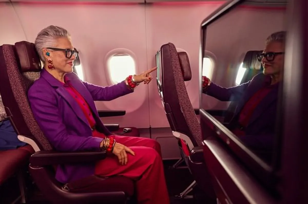 Person sitting in Virgin Atlantic Economy Delight seat, pointing at the screen in front of them.
