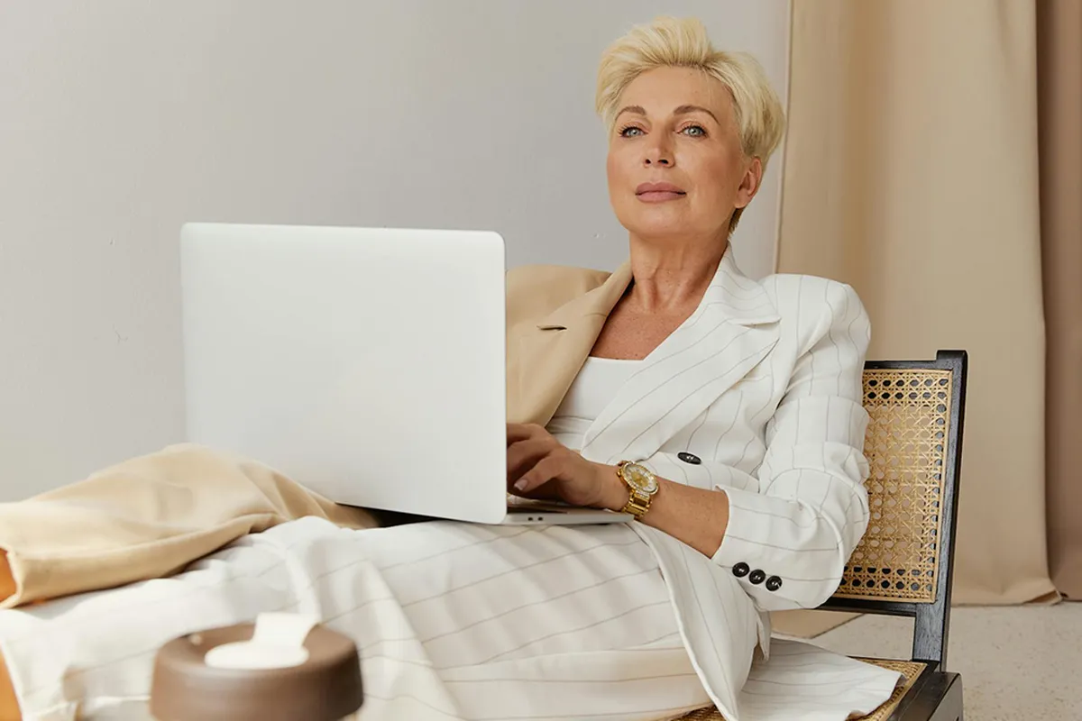 A woman in a white pinstripe suit choosing the travel insurance, using a laptop.