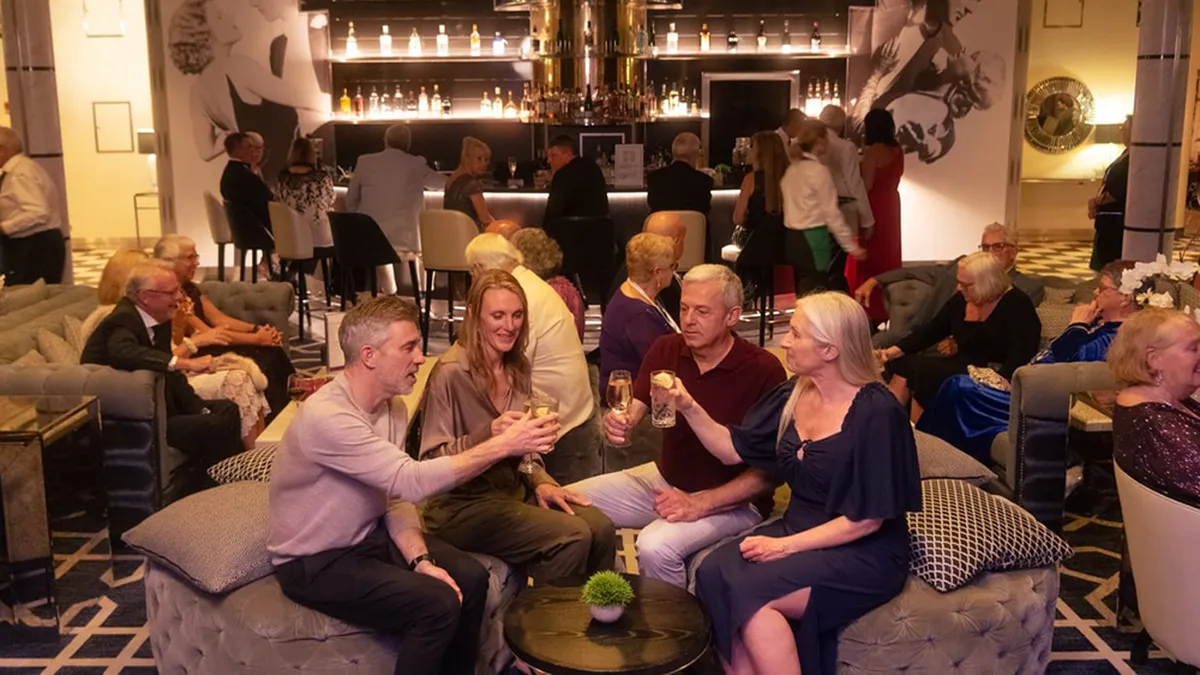 A group of people sitting in a Raffles lounge bar, toasting with drinks.