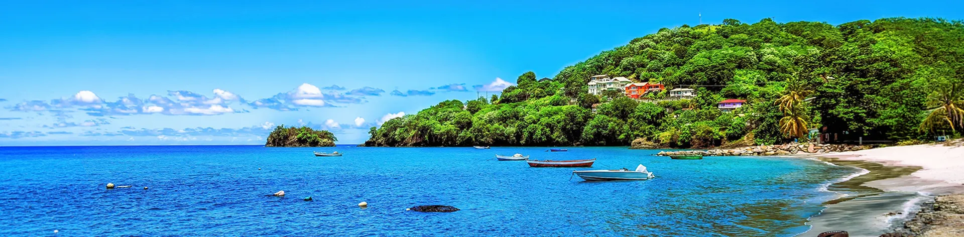 Calm blue sea with small boats, a sandy shoreline in Kingstown Saint Vincent