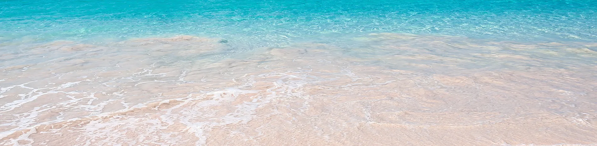 Turquoise waves gently lap against a sandy beach in Bridgetown, Barbados