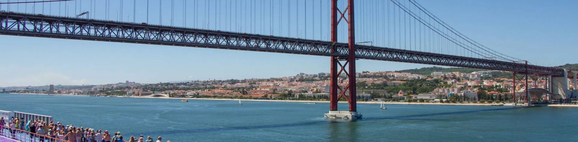 A busy top deck on Ambition cruise ship whilst sailing out of Lisbon under the bridge