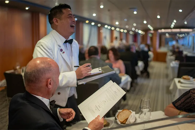 A waiter takes an order from a seated man in Buckingham restaurant on Ambition