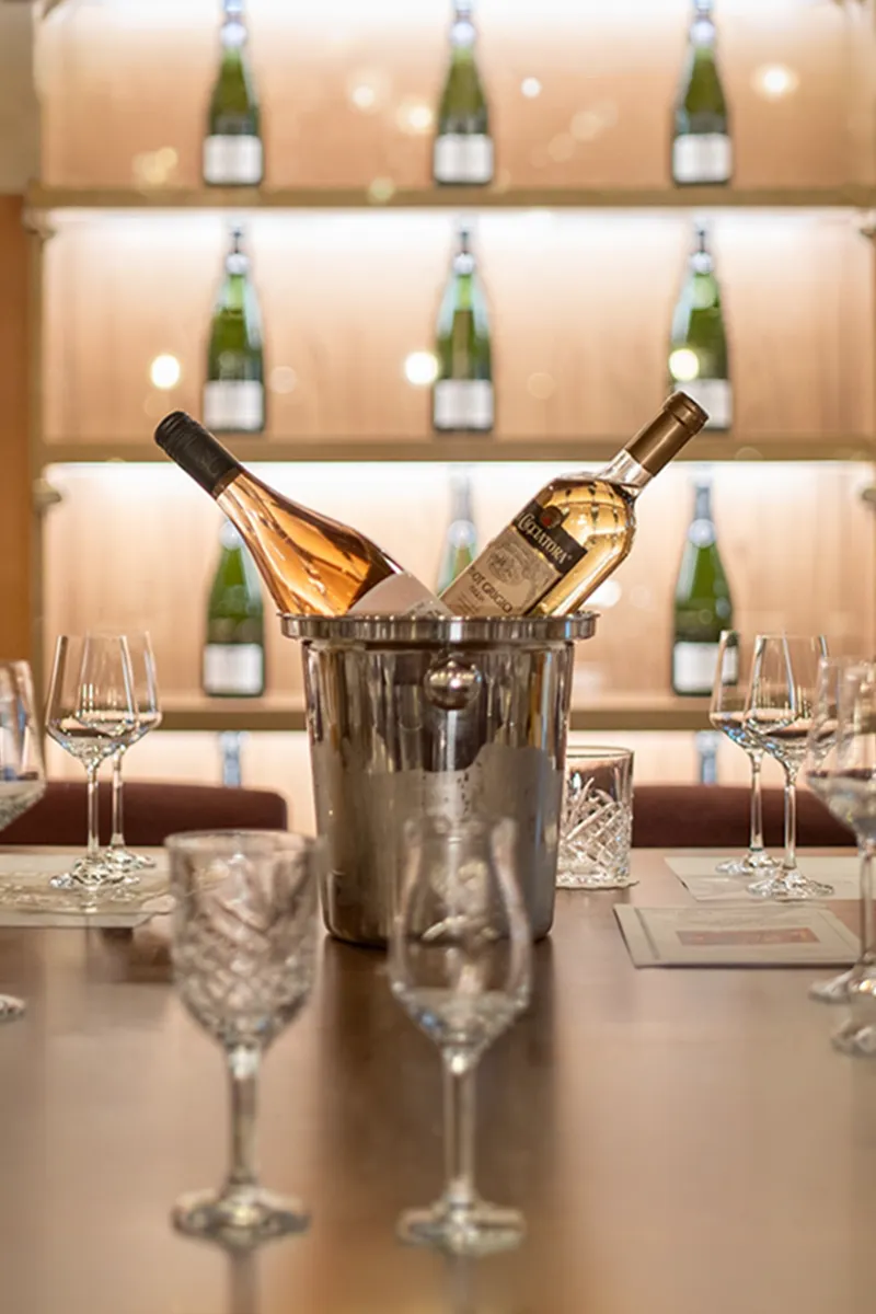 A table set with multiple wine glasses and two bottles of rosé in an ice bucket.