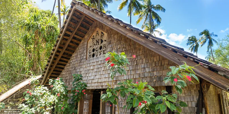 Rustic wooden building with a sign reading "Bar and Cocoa House,"