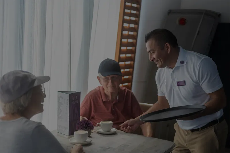 A waiter serves two guests seated at the coffee house