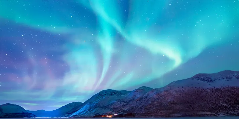Northern lights illuminate the night sky snowy mountains