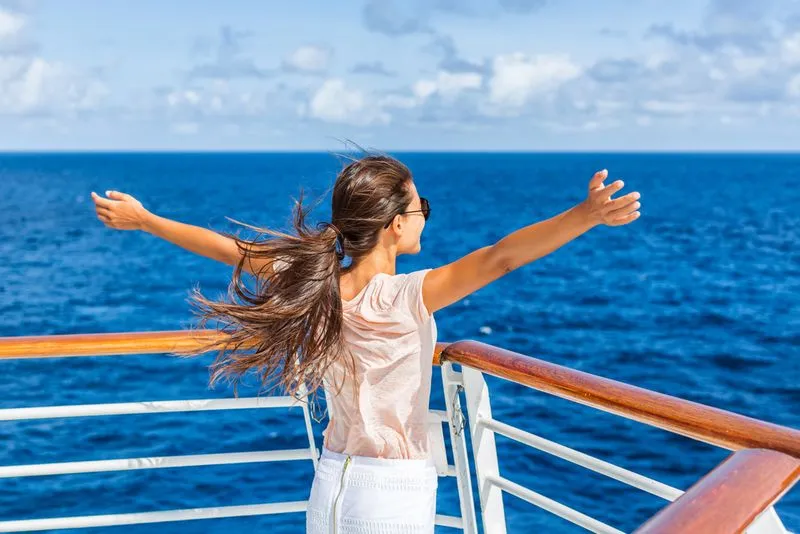 Woman with arms spread wide on cruise ship