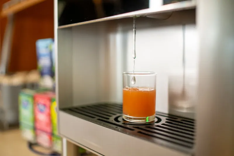 A glass being filled with juice from a dispenser
