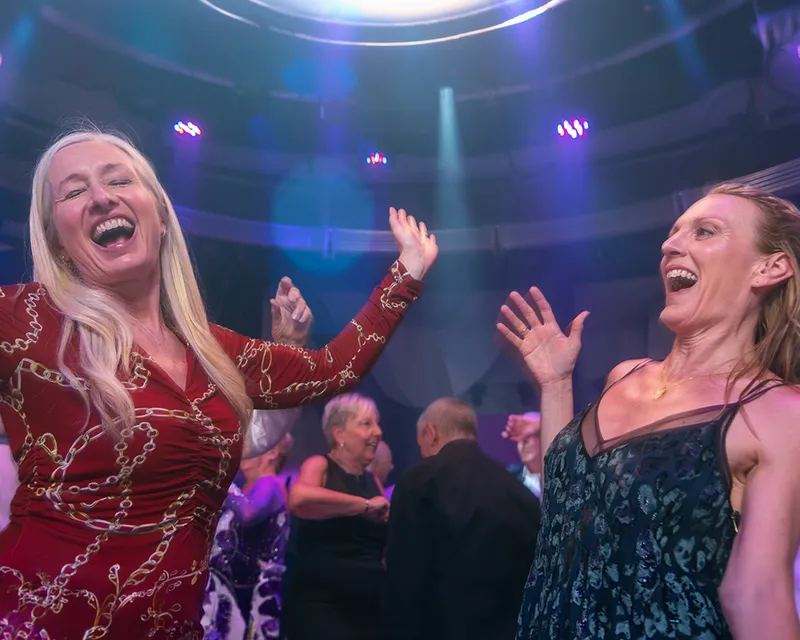 Two women joyfully dancing and laughing on the ambassador dance floor