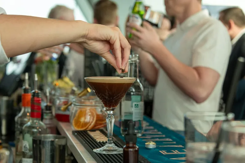 A bartender garnishes an espresso martini at a bar