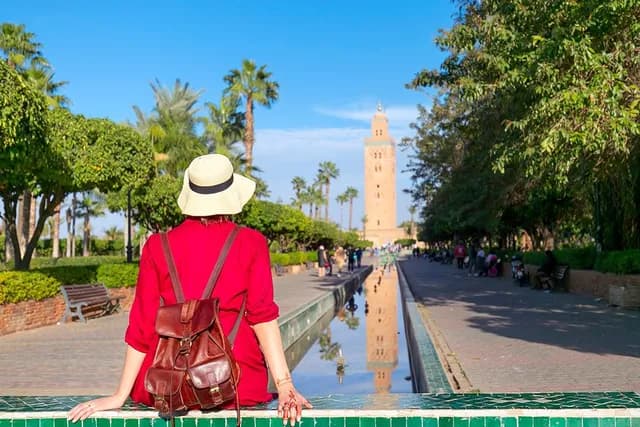 Young woman dressing in red with hat looking the mosque of Koutoubia in Marrakesh