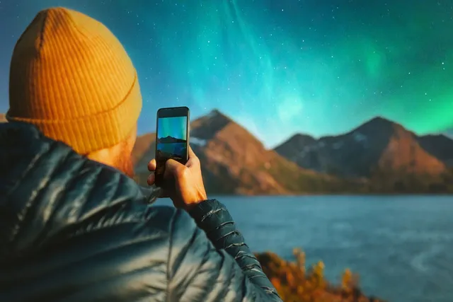 Person using their phone to photograph the Northern Lights