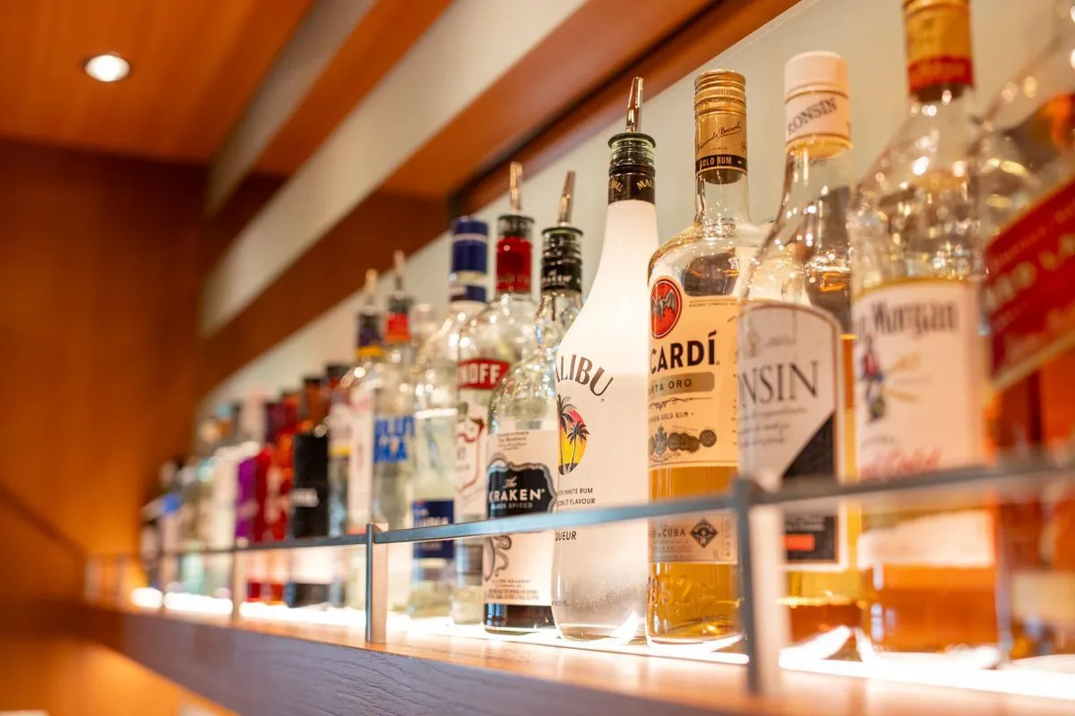 A variety of liquor bottles displayed on a shelf in a bar.