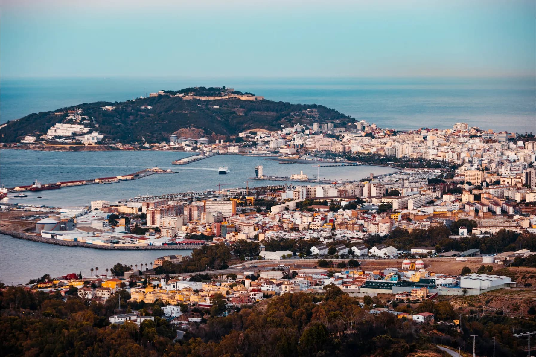 General view of the bay of Ceuta at sunset with Mount Hacho in the background while a ferry enters through the mouth of the port