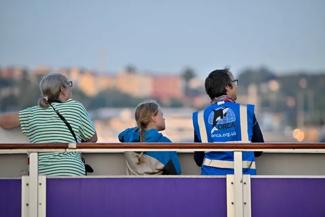 People on a ship look out over the water, one is an ORCA representative