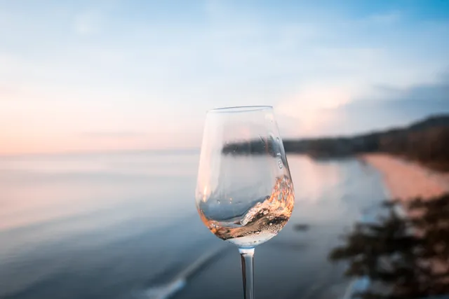 A glass of wine in front of a beach.