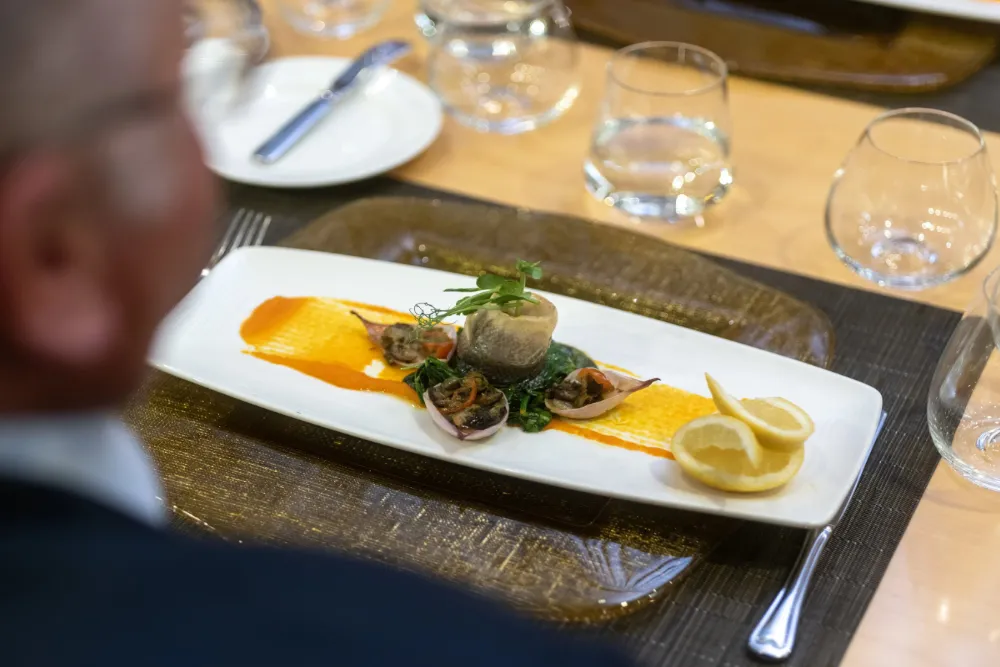 The view over a man’s shoulder of his meal on board an Ambassador Cruise