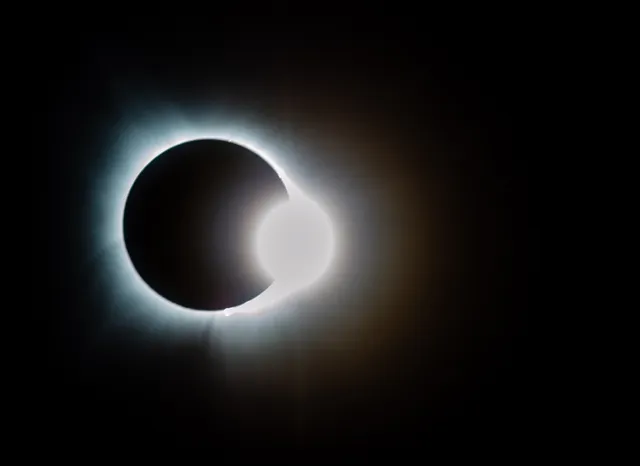 The moon moving in front of the sun during a total eclipse.