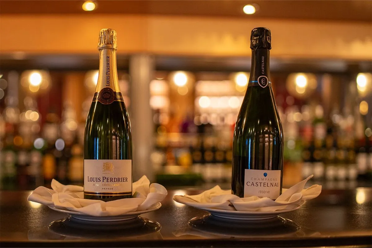 Two bottles of champagne, Louis Perdrier and Castelnau, displayed on a bar counter