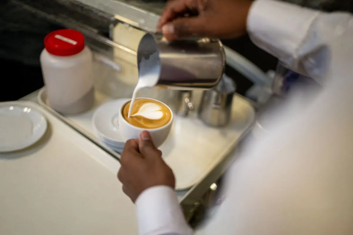 A person pours steamed milk into a cup of coffee
