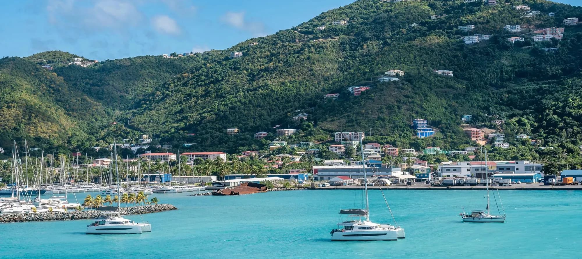 Boats sail on turquoise water near a harbor in Road Town, Tortola
