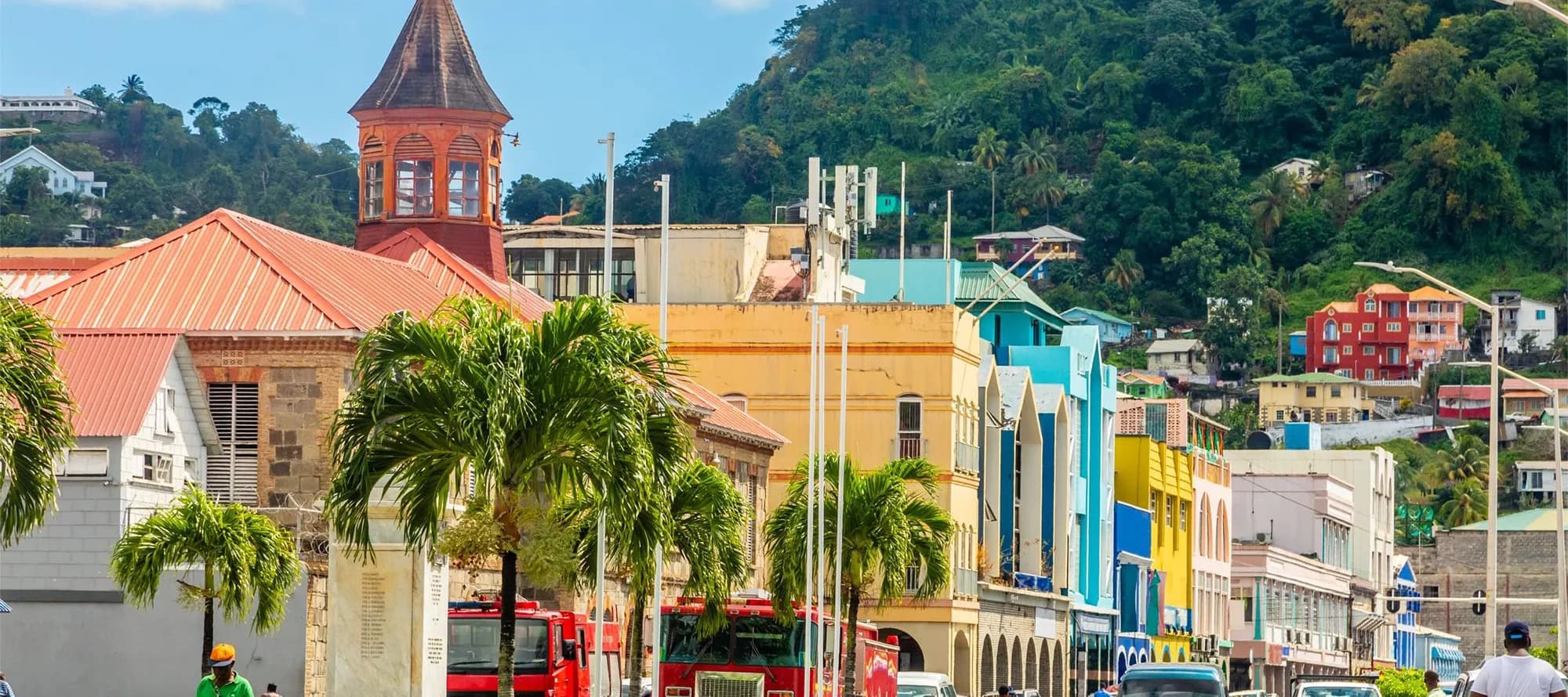 Street view of Kingstown, Saint Vincent with colorful buildings, palm trees and a backdrop of green hills