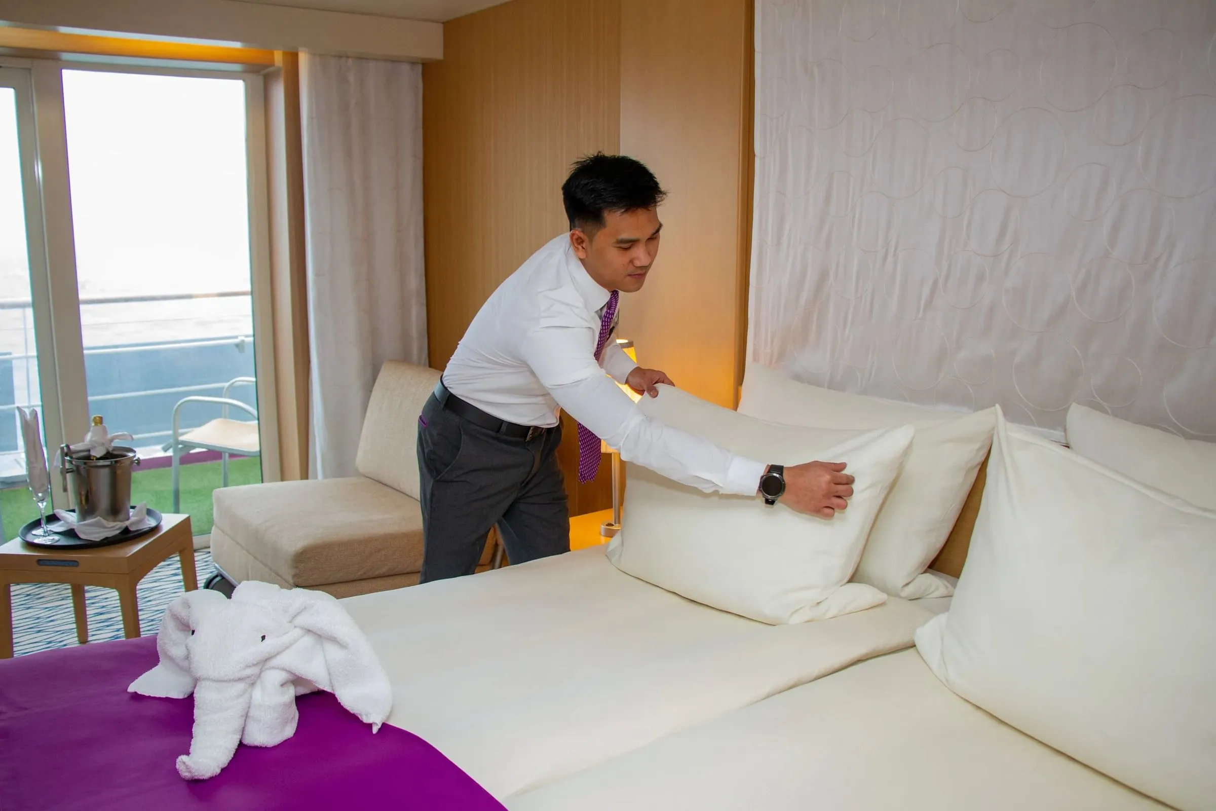 Ambassador crew making a bed in a balcony cabin