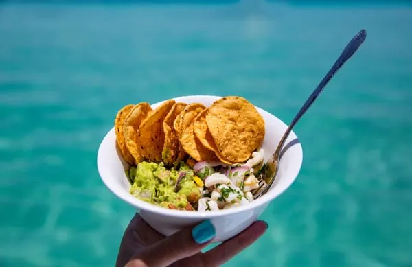 Woman Holding Fresh Ceviche Guacamole and Tortilla Chips Snack Bowl Made in Tropical Paradise
