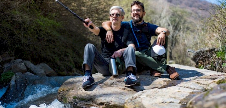 Father and adult son sat next to a river